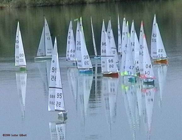 A fleet rounds the windward mark in very light airs